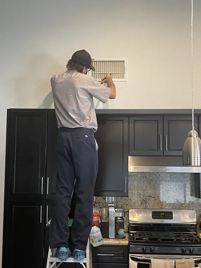Technician inspecting an air vent during HVAC service in Fishersville